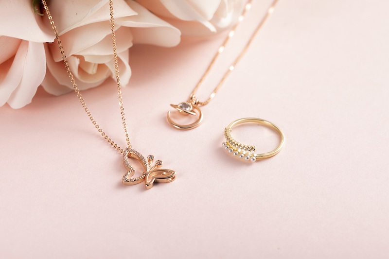 High angle shot of a beautiful ring and necklaces on a pink surface